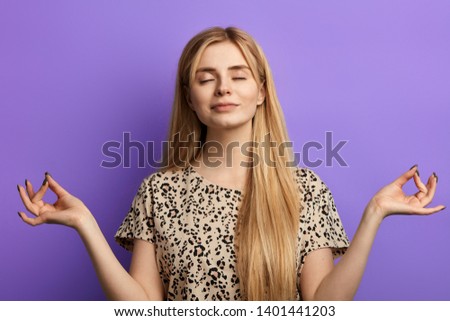 Gorgeous youngfair-haired woman dressed in light blouse keeping eyes closed while meditating. close up photo. concentration, meditation, strength of thoughts