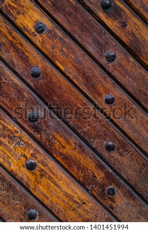Old vintage wooden door with metal furniture.  Brown wooden fence background texture.