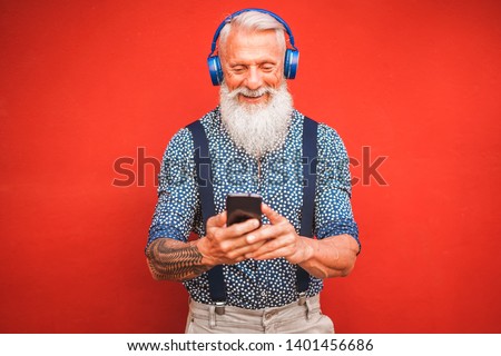 Trendy senior man using smartphone app with red backgorund - Mature fashion male having fun with new trends technology - Tech and joyful elderly lifestyle concept - Focus on his face