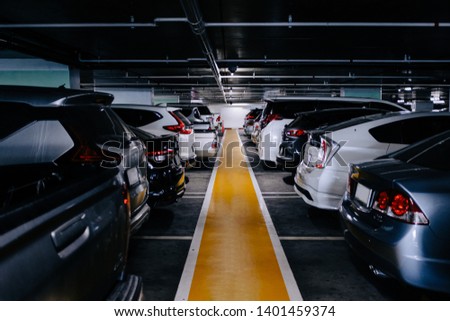 Many cars parked in the parking, interior of parking garage with yellow line.