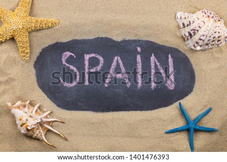 Handwritten word SPAIN written in chalk, among seashells and starfishes. Top view