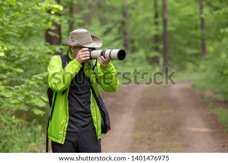 Photographer with a large long-focus lens takes pictures in the forest. concept of spending holidays 2020 due to coronovirus.
