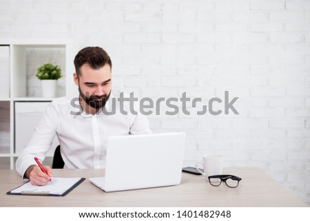 portrait of cheerful bearded businessman or student using laptop