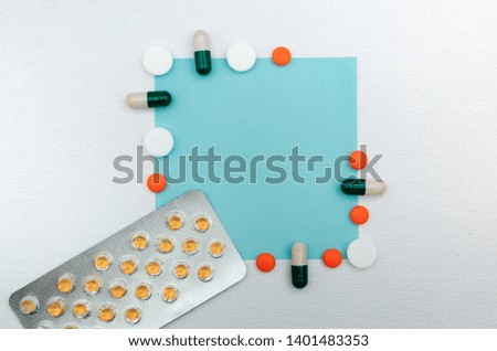 Creative layout made of variety of tablets and capsules. Flat lay. Pharmaceutical advertising background - blue square on white pearl texture background