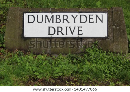 Street Name Sign for Dumbryden Drive on Carved Stone Surrounded by Green Grass in Edinburgh