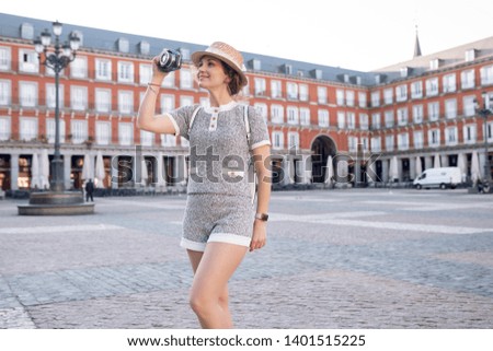 curly white girl tourist in a hat with a camera smiling photographs and exploring the city