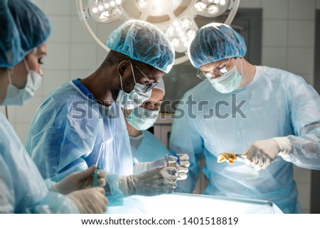 young african assistant helping the doctor to cut the body of patient. close up photo