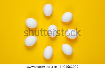 Bullying concept with eggs on yellow background. Top view, minimalism