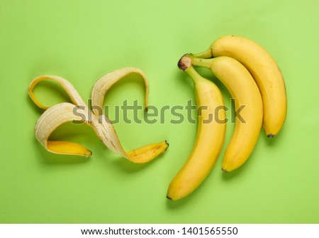 Minimalism fruit concept. Bunch of bananas and banana skin on green background. Top view