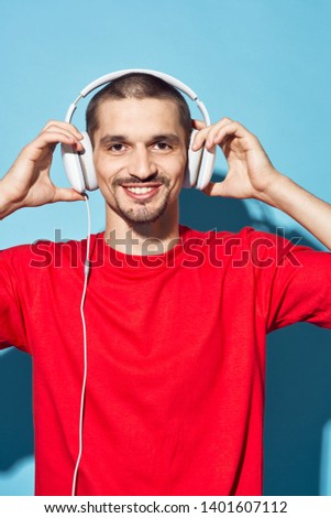 smile man listens in headphones white music on a blue background