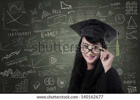 Happy asian woman in graduation gown at class