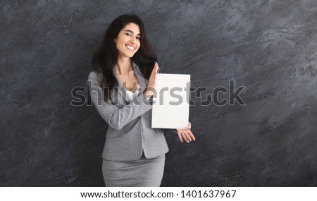 Happy Business Woman Showing Blank Signboard For Advertisement Over Grey Wall
