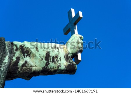 Christian cross in copper rust covered hand isolated on blue sky background - concept Christianity Catholicism religion Christ god church forgiveness exorcism belief faith strength prayer worship