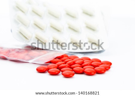 Red pills with plastic bag and capsule in white background