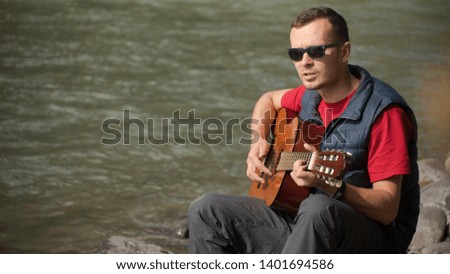 playing the guitar on the background of glare from the water