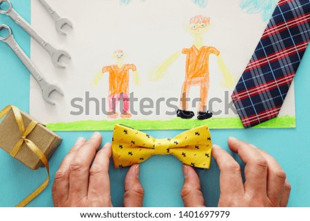 Father's day concept. gift box, tie, funny moustache and child's painting over wooden background. top view, flat lay