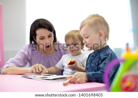 Babysitter reads book to kids in nursery