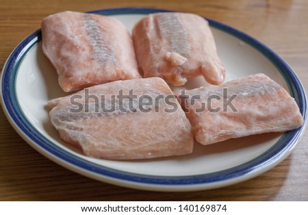 Frozen salmon steaks thawing on a plate Royalty-Free Stock Photo #140169874