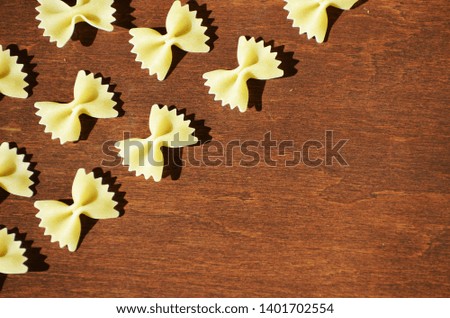 Pasta in a shape of bow isolated on wooden background, macaroni background,photo