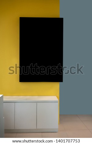Black mockup frame hanging on yellow wall in modern interior for information or advertising