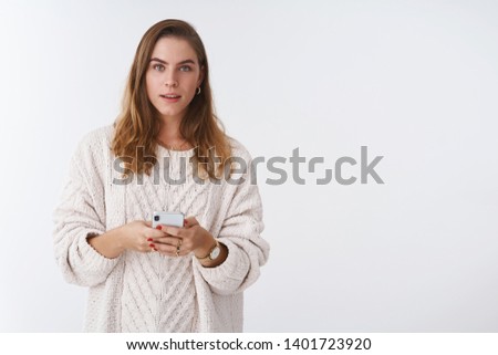 Waist-up shot curious cute casual modern attractive woman short haircut wearing loose trendy cozy sweater holding smartphone listening you consulting how answer message dating app