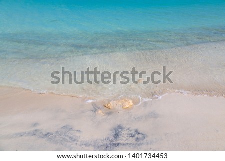 A full frame photograph looking at the turquoise sea lapping a sandy beach, on the Caribbean Island of Antigua