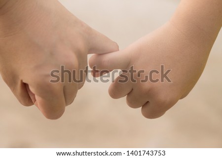 The young and the old hooking each other's little finger. The image gives senses of commitment, companion, and caring
