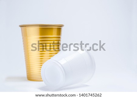Two colored plastic cups one golden and one white for parties and drinks on a white background