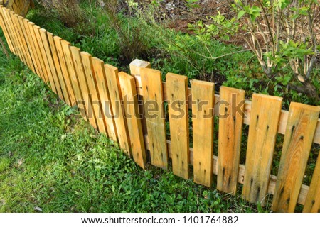 Brown wooden fence in garden green background with parallel plank old