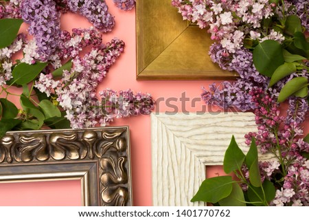 Decorative picture frames and spring lilac flowers on pink background. Framing workshop concept.