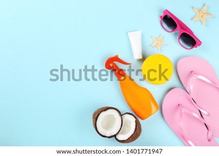 Sunscreen bottles with coconuts, sunglasses and flip flops on blue background