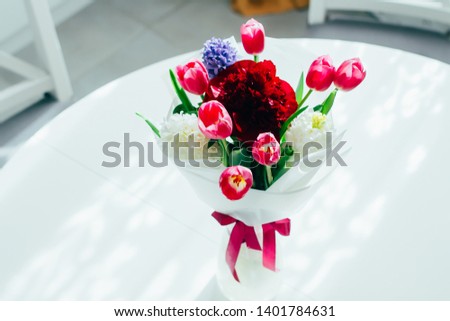 Beautiful bouquet of fresh tulips, peony and hyacinth on a table in the kitchen