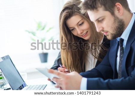 Young businessman discussing something with his colleague, and using a digital tablet together