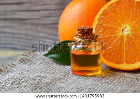 Orange essential oil in a glass bottle and fresh fruits on old wooden table.Citrus oil for skin care, spa, wellness, massage, aromatherapy and natural medicine.Selective focus. Royalty-Free Stock Photo #1401795983