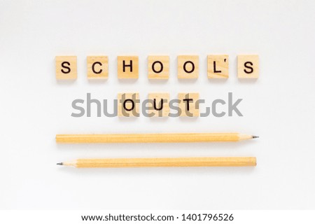 School's out. The inscription in wooden letters on a white background. Pencils on a white background