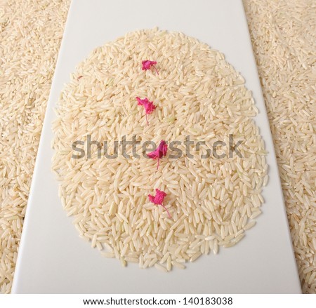 closeup brown rice on plate, decoration with pink flowers 