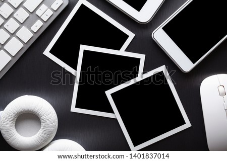 Three classic paper photo frames, mobile phone, tablet, keyboard, computer mouse and headphones