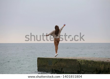 happy young girl with curly hair dancing and jumping on the sea