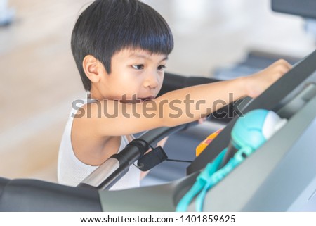Asian child is running on treadmill in fitness gym
