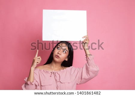 Young Asian woman point to blank sign on pink background
