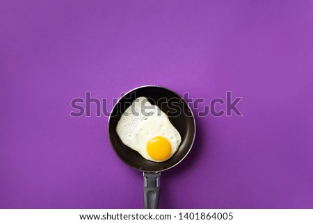 Creative food concept with fried egg on pan over violet background. Top view. Creative pattern in minimal style. Flat lay.