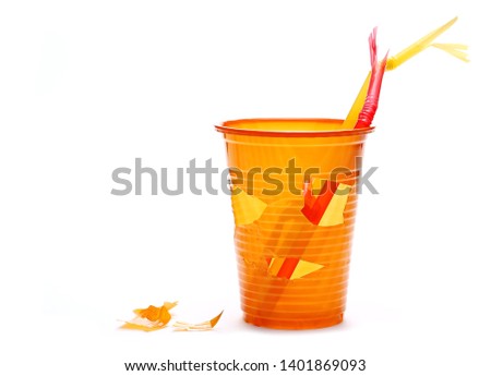 Chopped orange plastic cups and straw in shape face isolated on white background