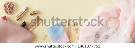 Flat lay of female home office desk on pastel yellow background. Panoramic backdrop, top view.