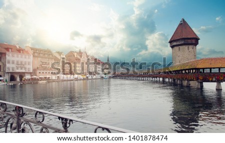 Tower and bridge across river in Lucerne, Switzerland during twilight hour.