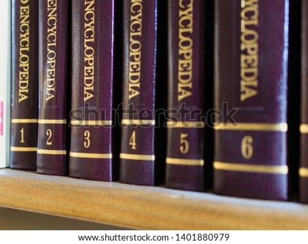 Few encyclopedia volumes, standing on a bookshelf, with close-up on golden volumes' numbers Royalty-Free Stock Photo #1401880979