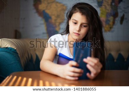 Portrait of cheerful modern children girl with smartphone in hands, on background of world map