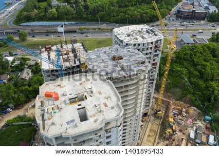 Aerial top view of construction site of modern concrete buildings with industrial machinery equipment, cranes, workers. Drone photo