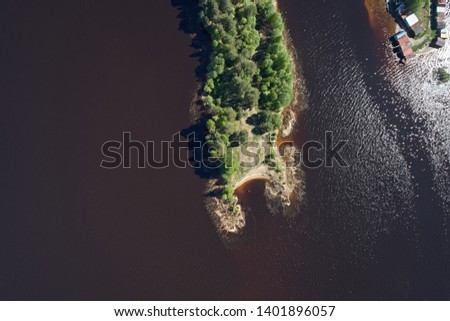 Top view of the peninsula in the dark water of the river and the shore of the earth, on a bright sunny day. Beautiful summer landscape, picture from the drone.