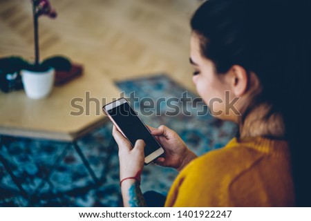 Selective focus on modern smartphone with mock up screen in hand of woman sending text message,cropped image of hipster girl installing application on mobile phone for chatting using wifi at home
