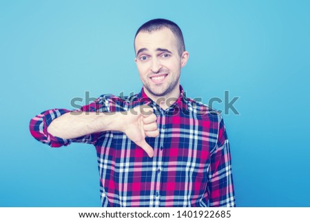 Attractive  man showed a thumb down, portrait, blue background, copy space